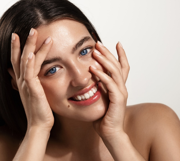 woman smiling with smooth, youthful-looking skin and hands framing her face